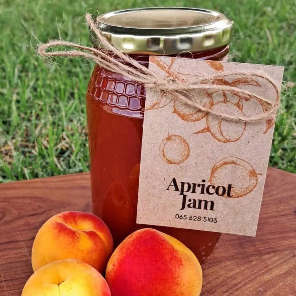 Homemade apricot jam in a glass jar with a golden lid, featuring vibrant orange color and a rustic Anita’s Kitchen label, perfect for baked goods and pancakes.